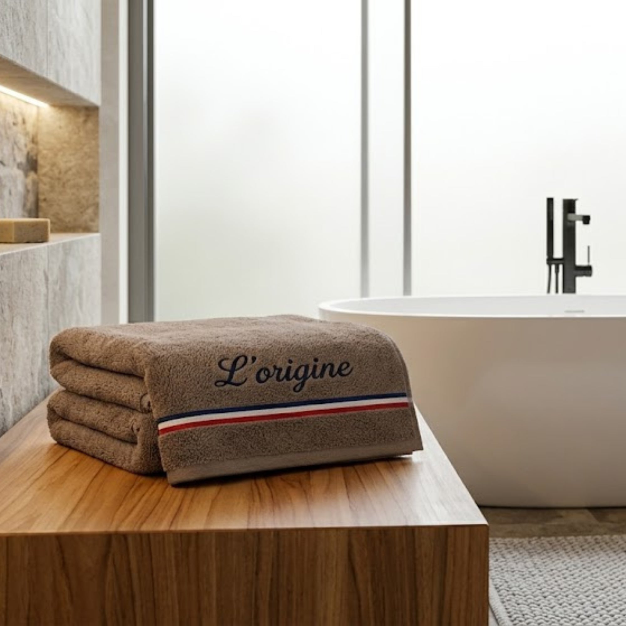 Serviette de bain marron chocolat en coton éponge avec une broderie L'origine avec un liseré tricolore bleu, blanc, rouge, pliée